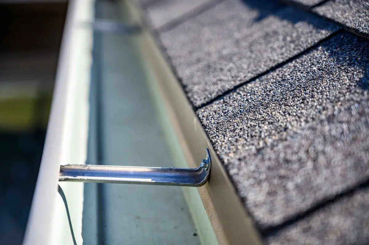 Close-up of a gutter hanger and drip edge on a shingled roof