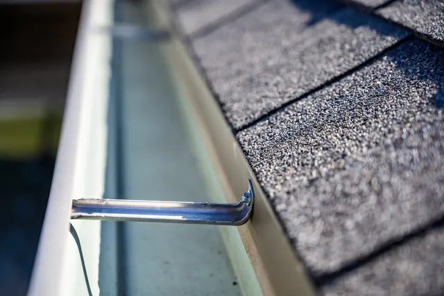 Close-up of a gutter hanger and drip edge on a shingled roof