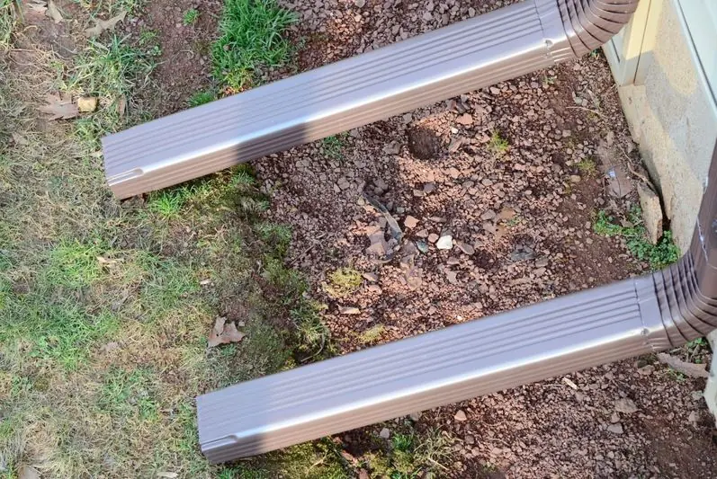 Freshly formed seamless aluminum gutter sections laid out at a job site