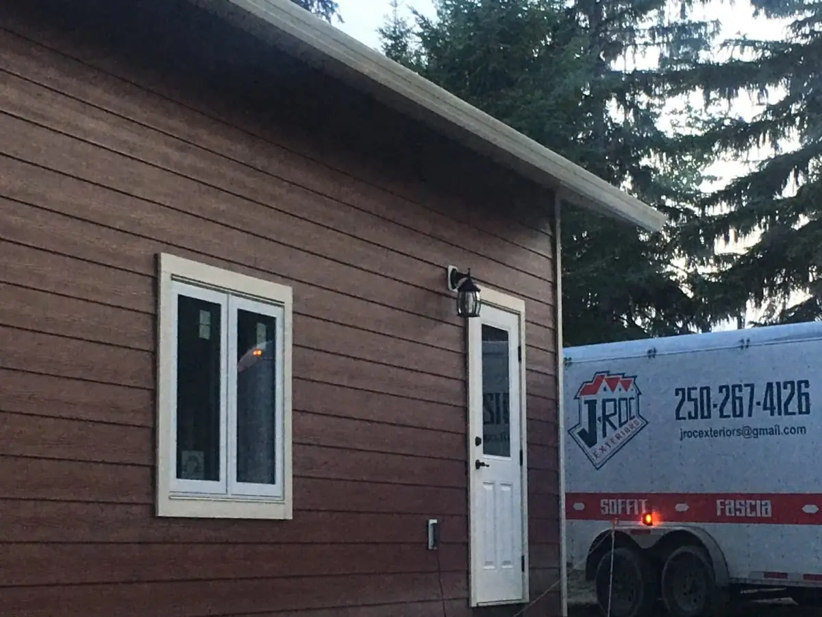 Red-sided home with the J-Roc Exteriors trailer on site