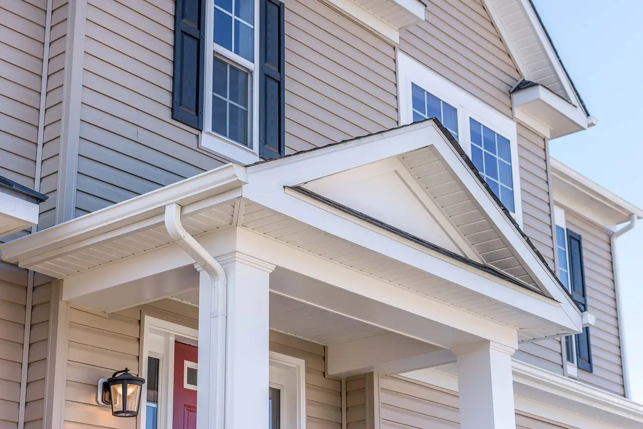 White vinyl siding with covered porch and dark shutters