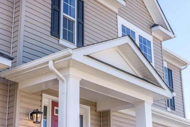 White vinyl siding with covered porch and dark shutters